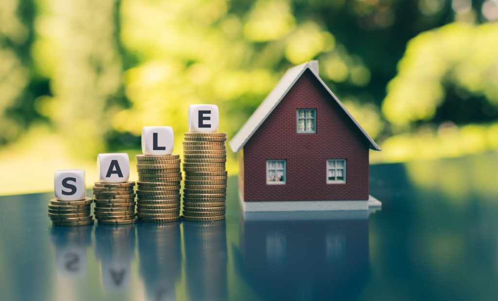 Stacks of coins increase in size as they reach a house. On top of each coin is a letter spelling SALE